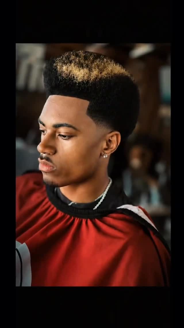 High-top fade with blond curls and a lined beard